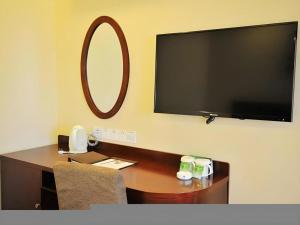 a desk with a television and a chair in a room at GreenTree Inn Qingdao Licang Shuyan Road Daweng Square Express Hotel in Laoshan +83 photos