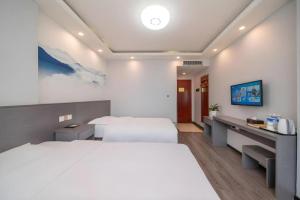 a bedroom with a large white bed and a desk at GreenTree Inn HanZhong Railway Station Beiyihuan Road Express Hotel in Shima