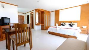 a bedroom with a bed and a table and a television at Phu View Talay Resort in Pattaya South