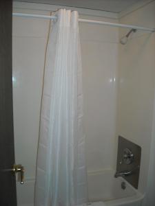 a bathroom with a shower with a white shower curtain at Red Carpet Inn Greensboro in Greensboro