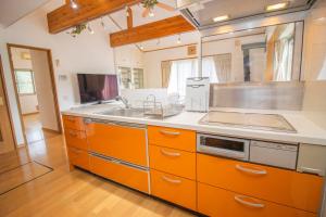 a kitchen with orange cabinets and a sink at 南伊豆ガーデンヴィラ in Minamiizu