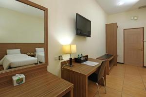 a hotel room with a desk and a bed and a mirror at Pondok Jatim Park Hotel & Cafe in Batu