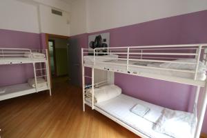 3 letti a castello in una camera con pareti viola di Panda Hostel a Milano