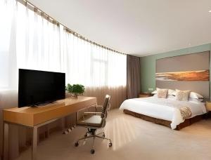 a bedroom with a bed and a desk with a television at Ramada Plaza by Wyndham Chuzhou in Chuzhou +9 photos