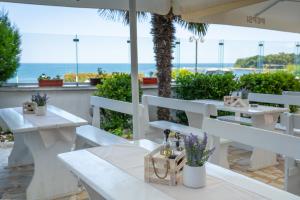 a restaurant with white tables and a view of the ocean at Elite Family Hotel in Kiten