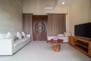 a living room with a couch and a tv and a table at Villa Dewi 3 in Ubud