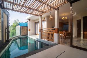 an indoor swimming pool with a patio and a house at Villa Dewi 3 in Ubud