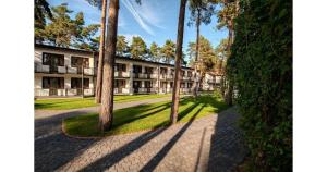 ein Apartmentkomplex mit Bäumen und einem Gehweg in der Unterkunft Chemar2 in Łeba