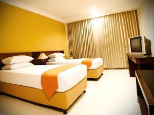 a hotel room with two beds and a television at Wonua Monapa Hotel Resort in Kendari