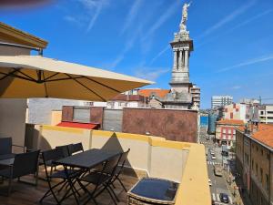 a table and chairs on a balcony with a clock tower at Ático Jovellanos in Gijón