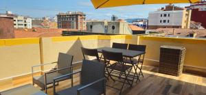 a balcony with a table and chairs on a roof at Ático Jovellanos in Gijón