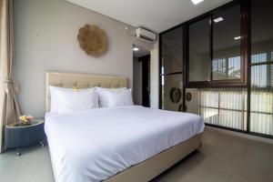a bedroom with a large bed with white sheets at Casa de Lily in Tabanan