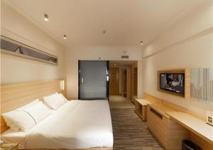 une chambre avec un grand lit blanc et une télévision dans l'établissement City Comfort Inn Yongzhou Jinshuiwan, à Guzhuting