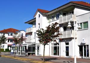 a white building with white balconies on a street at Ferienwohnung Wellenreiter 200 m zum Strand Fewo strandnah mit Balkon Parkplatz Wlan in Karlshagen