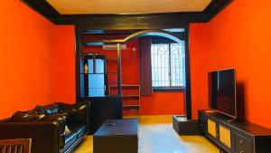 a living room with orange walls and a television at The house where time is wasted under the road in Chongqing