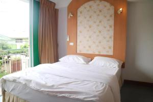 a bedroom with a large white bed with a window at Diamond Sweet Hotel in Bangkok