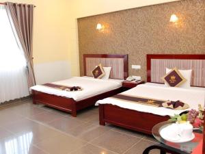 a room with two beds and a table with a table at Tran Vinh Hotel in Bạc Liêu +119 photos