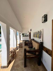 a living room with wooden furniture and a wall with windows at Amani Beach Villa- Bwejuu in Bwejuu