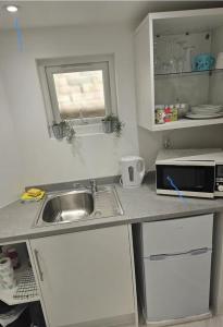 Una pequeña cocina con fregadero y microondas. en Single Cosy Bedroom in Dartford- Private Entrance for guest, en Kent 1 foto más