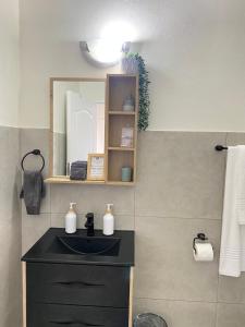 een badkamer met een zwarte wastafel en een spiegel bij Nunu's Self Catering Apartment in Paarl