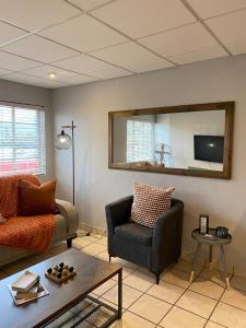 een woonkamer met een bank, een stoel en een spiegel bij Nunu's Self Catering Apartment in Paarl