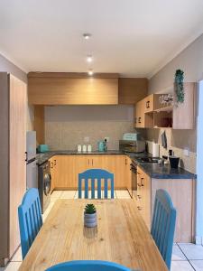 a kitchen with a wooden table and blue chairs at Nunu's Self Catering Apartment in Paarl