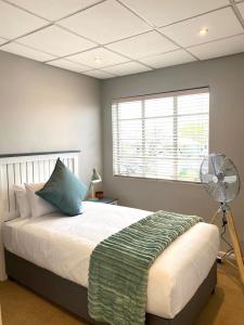 een slaapkamer met een bed, een ventilator en een raam bij Nunu's Self Catering Apartment in Paarl