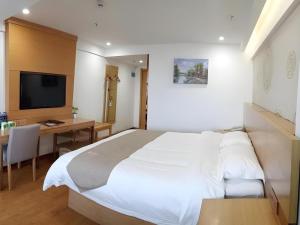 a bedroom with a large white bed and a desk at GreenTree Inn Anqing Qianshan County Sunshine City Express Hotel in Qianshan +58 photos