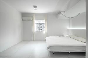 a white room with a bed and a window at Daydreaming House under the Road in Chongqing