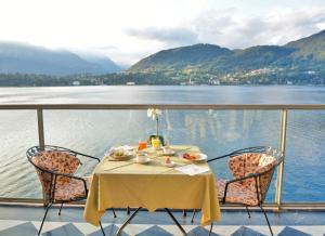 a table and chairs on a balcony with a view of a lake at Grand Hotel Cadenabbia in Griante Cadenabbia