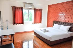 a bedroom with a bed and a red brick wall at Bussarakam Place Hotel in Ban Chamun (2)