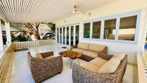 a porch with a couch and chairs and a table at Tiki White House in Ban Nong Chaeng