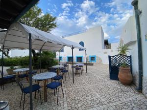 un patio con tavoli e sedie sotto un ombrellone di Hotel Aura a Vulcano