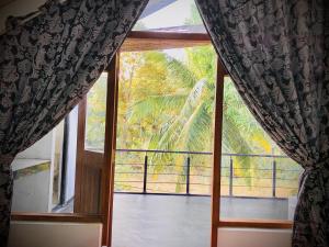 a window with a view of a palm tree at Sigiri Holiday Bungalow in Sigiriya