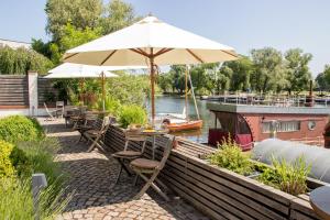 eine Terrasse mit einem Tisch mit einem Sonnenschirm und einem Boot in der Unterkunft Havelfloß Apartments in Brandenburg an der Havel