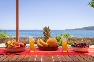a table with fruit and juice on a table with the ocean at Το Καμίνι, πέτρινη κατοικία πάνω στη θάλασσα The Kiln House Kamini, Retreat on the beach in Aspropótamos