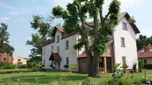duży biały dom z drzewem w ogrodzie w obiekcie Na Plebanii w mieście Jaszkowo