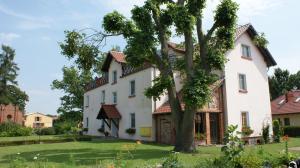 a large white house with a tree in the yard at Na Plebanii in Jaszkowo