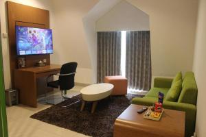 a living room with a green couch and a tv at Pomelotel Patra Kuningan Jakarta in Jakarta