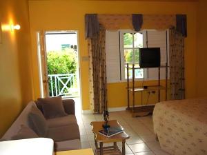 a living room with a couch and a tv at Gold Nugget Hotel in Negril