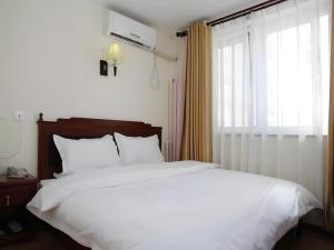 a bedroom with a large white bed and a window at Beijing Yi Jia Hotel in Beijing