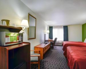 a hotel room with a bedroom with a bed and a desk at Quality Inn & Suites Airport in Austin