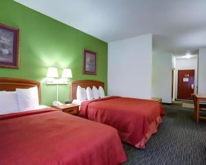 two beds in a hotel room with green walls at Quality Inn & Suites Airport in Austin