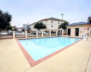 a large swimming pool with blue water in front of a building at Quality Inn & Suites Airport in Austin