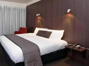 a hotel room with a large bed and a telephone at The Riccarton Hotel in Christchurch