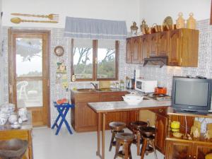 a kitchen with a tv and a table with stools at Casa do Costa in Fajã