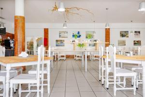 a dining room with white tables and white chairs at Zdrowotel Łeba in Łeba
