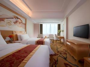 a hotel room with two beds and a flat screen tv at Vienna Hotel Guangdong Qingyuan Wanda Plaza Xincheng Beijiang in Qingyuan