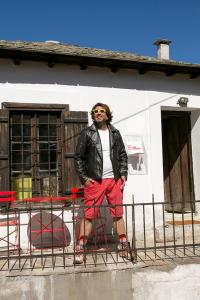 a man in red shorts and a leather jacket standing next to a fence at The Pelion Manifesto 2 in Agios Georgios Nilias +14 photos