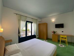 una camera da letto con un letto, una scrivania e una televisione di Hotel Aura a Vulcano